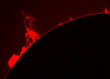 Snímek sluneční protuberance z protuberančního koronografu, kde je obraz vlastního slunečního disku zastíněn kovovým terčem.